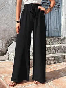 Detailed view of women's black seersucker textured wide-leg pants with drawstring waist