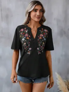 Detailed view of women's black top with colorful floral embroidery and lace trim.