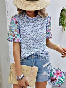 Détail de broderie florale et d'imprimé sur une blouse d'été avec col montant ondulé.
