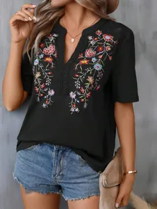 Detailed view of women's black V-neck top with colorful floral embroidery and lace trim