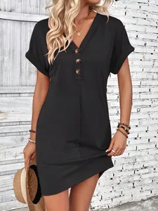 Detail view of a black summer dress featuring a buttoned V-neck and rolled sleeves