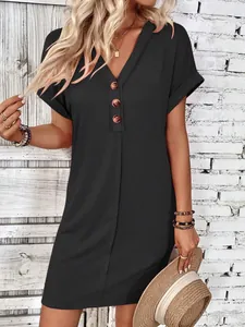 Detail view of a black V-neck summer dress with decorative buttons and rolled sleeves.