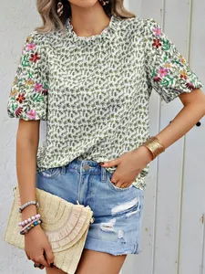 Vue détaillée d'une blouse d'été brodée de fleurs avec col montant volanté et motif vert.