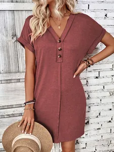 Detailed view of v-neck button dress with rolled sleeves in a rustic outdoor setting.