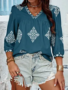 Detailansicht der petrolfarbenen V-Ausschnitt Bluse mit weißen geometrischen Mustern.