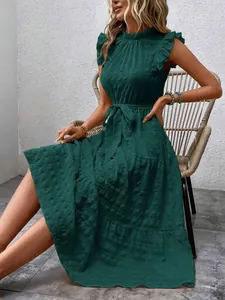 Detailed view of emerald green textured dress with ruffled wing sleeves and tie waist.