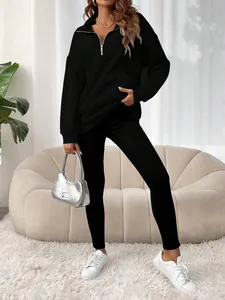 Vue complète d'une femme portant un sweat-shirt noir à demi-zip et un legging assorti