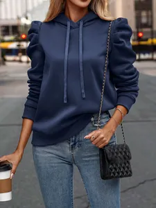 Detailed view of navy blue puff sleeve hoodie with drawstring hood and city backdrop