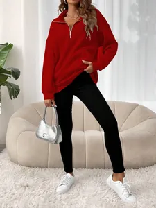 Sweat-shirt rouge oversize à fermeture éclair stylé avec leggings noirs et baskets blanches.