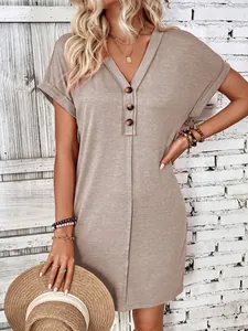 Detailed macro shot of a khaki V-neck summer dress featuring button details and rolled sleeves