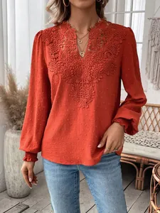 Detail of orange V-neck blouse with intricate lace crochet and swiss dot texture.