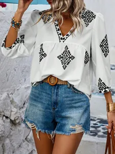 Detail der weißen V-Ausschnitt-Bluse mit aufwendiger schwarzer Stickerei im Ethno-Stil