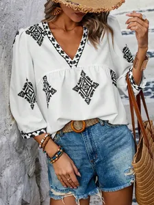 Detail der weißen V-Ausschnitt Bluse mit schwarzen geometrischen Mustern und 3/4 Ärmeln.