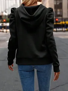 Back view of a stylish black women's puff sleeve hooded sweatshirt on a city street
