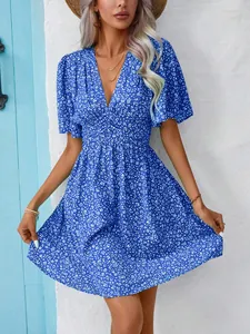 Close-up detail of a vibrant blue V-neck floral dress with high waist and pleated hem