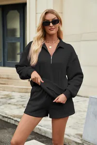 Detailaufnahme eines schwarzen Damen-Sweatshirts mit Viertelreißverschluss und passenden Shorts