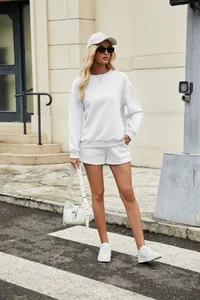 Close-up outdoor full body shot of a woman in a white sweatshirt and matching shorts set
