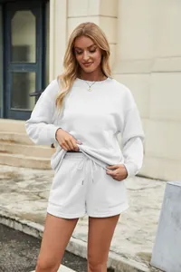 Model wearing a white two-piece lounge set in an outdoor street style setting