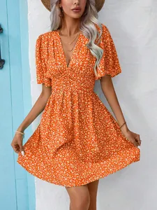 Close-up detail of a vibrant orange V-neck floral dress with high waist and flutter sleeves