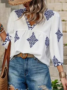 Detailansicht einer weißen Boho-Bluse mit V-Ausschnitt und blauer Stickerei