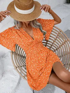 Detail view of a vibrant orange floral V-neck summer dress with high waist and pleated skirt