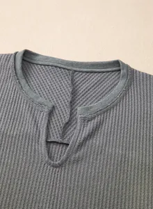Primer plano de la textura de punto gofrado gris en el cuello en V de una sudadera informal para mujer.
