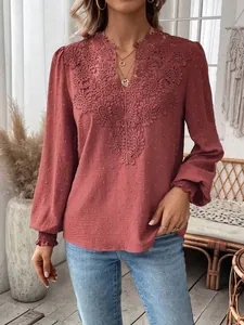 Detailed view of the V-neck lace trim and Swiss dot fabric on a terracotta blouse.