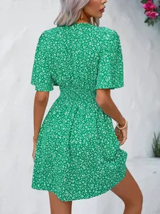 Detailed back view of a green ditsy floral summer dress with a smocked high waist and pleated skirt