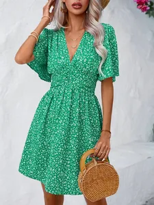 Detailed view of green V-neck floral dress with pleated waist and flutter sleeves