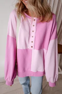 Detailed view of a pink patchwork sweatshirt with button-up front and ribbed cuffs