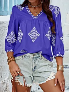 Nahaufnahme einer blauen V-Ausschnitt Bluse mit weißer Stickerei und Dreiviertelärmeln