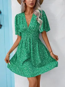 Front view detail of a vibrant green floral V-neck high waist pleated mini dress