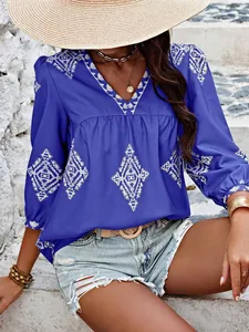Nahaufnahme einer blauen V-Ausschnitt-Bluse mit weißer Stickerei und Sommer-Accessoires