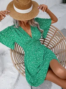 Macro view of an elegant green floral V-neck dress worn by a model in a wicker chair