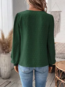 Back view detail of a dark green long-sleeved Swiss dot blouse in a cozy boho setting