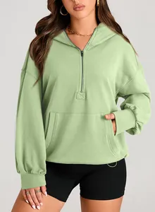 Detail of mint green half-zip hoodie featuring front kangaroo pocket and ribbed cuffs.