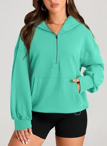 Detail of a teal half-zip hooded sweatshirt featuring a front kangaroo pocket
