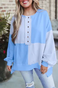 Oversized color block sweatshirt with button detail worn by a smiling model outdoors