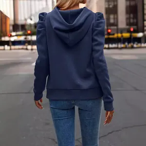 Navy blue hooded sweatshirt with stylish puffed shoulders for women in a city street back view