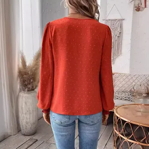 Back view of a chic rust orange long-sleeve casual top with elegant textured dot patterns.