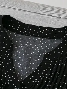 Detailansicht eines V-Ausschnitt Chiffon-Oberteils mit klassischem schwarz-weißem Punktmuster