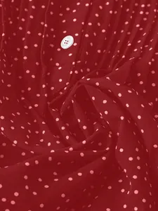 Hochwertiges Makro-Detail von rotem Chiffon-Stoff mit Polka-Dots und weißem Knopf