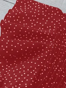Nahaufnahme von dunkelrotem gepunktetem Chiffonstoff mit eleganter plissierter Textur
