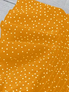 Detailaufnahme eines gelben Chiffonstoffs mit klassischem weißen Punktmuster-Design