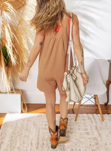 Back view of a sleeveless waffle knit solid romper styled with western boots