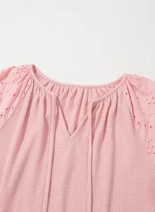Detailansicht des rosa Waffelstrick-Tops mit zarten Lochstickereien an den hohlen Ärmeln.