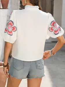 Vue arrière d'une blouse blanche élégante avec broderie florale sur les manches bouffantes
