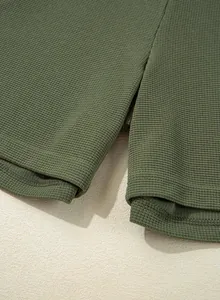 Close-up of olive green waffle knit fabric and stitched hem details on romper
