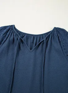 Detailansicht eines marineblauen Waffelstrick-Tops mit V-Ausschnitt und Stickerei-Ärmeln