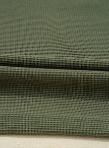 Macro detail of high-quality olive green waffle knit fabric showing premium texture.